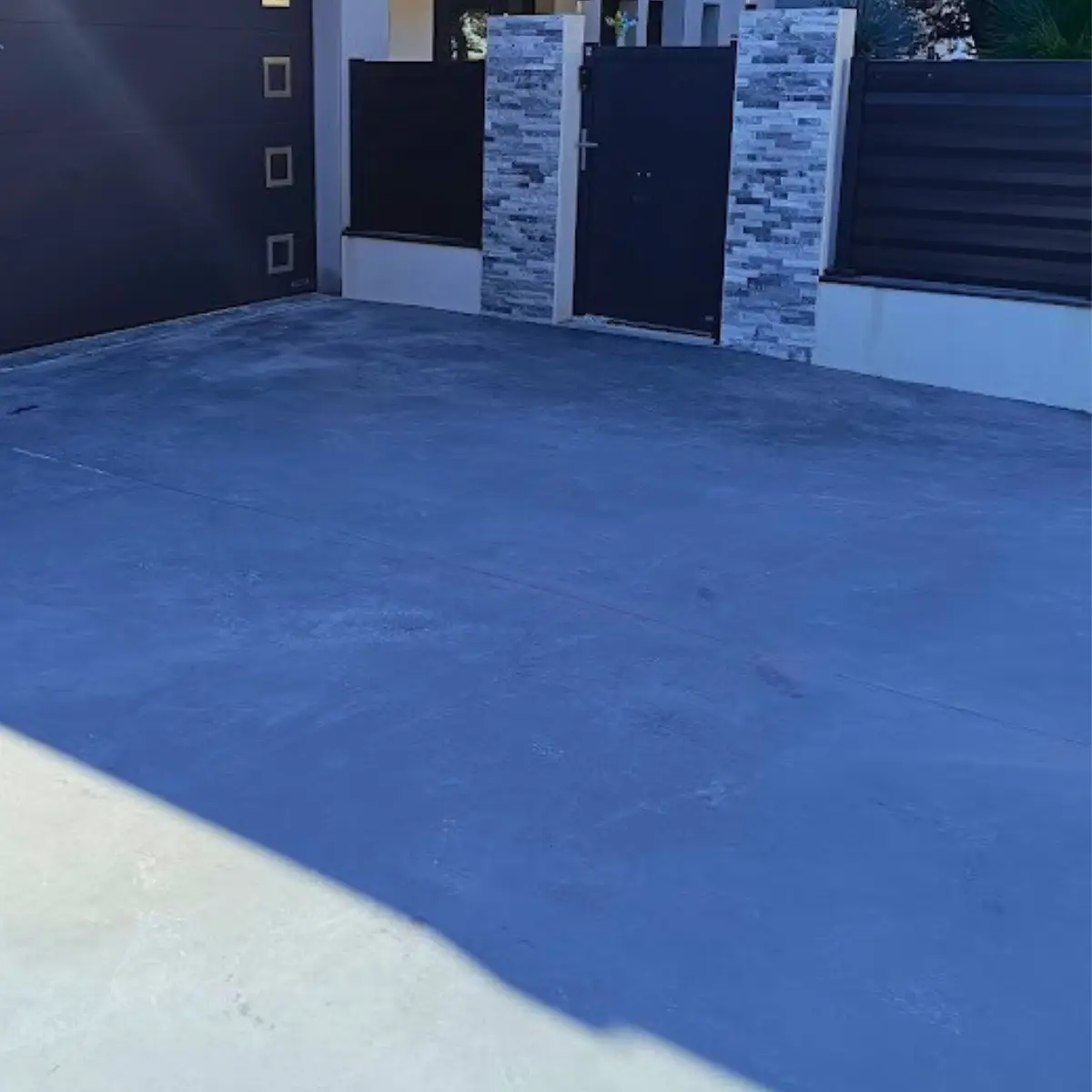 Allée de maison en béton taloché anthracite devant portail moderne